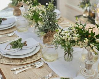 Dining table decorated with greenery, flowers and tableware