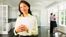 Female real estate agent standing in front of a couple who is viewing her house