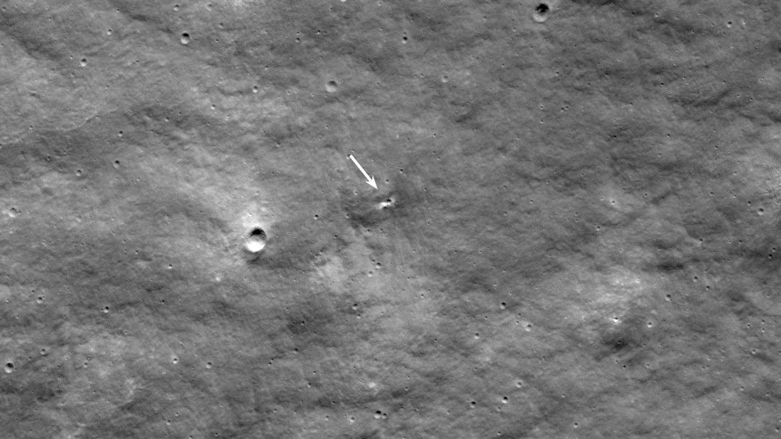 The moon with an arrow pointing at a small new crater