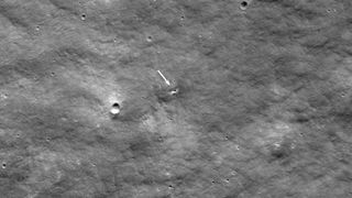 The moon with an arrow pointing at a small new crater