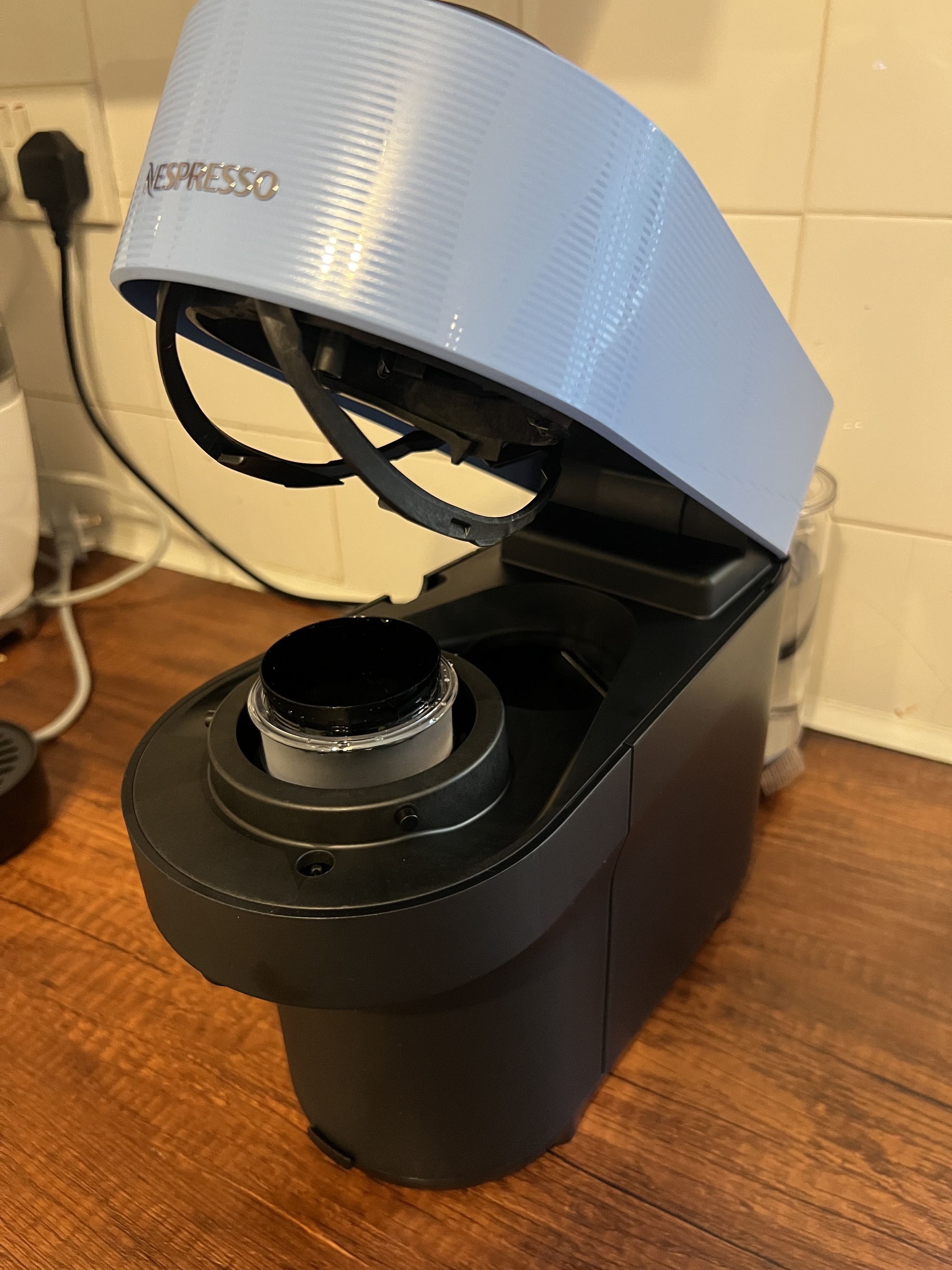 Image of Nespresso' Vertuo Pop machine in light blue and black open and showing the inside of the machine.