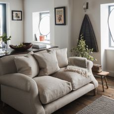 A living room with a beige two-seater sofa and minimal, rustic decor made with natural materials