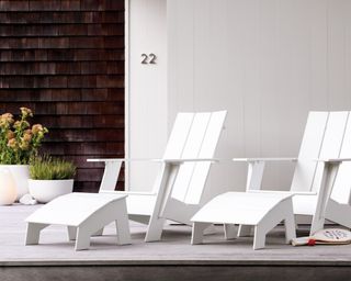 A pair of white HDPE Adirondack chairs on a contemporary front porch