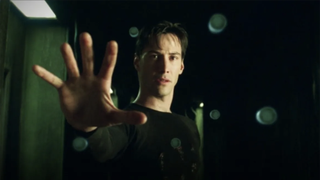 Keanu Reeves is playing Neo in The Matrix holding out his hand as objects float in the air around it.