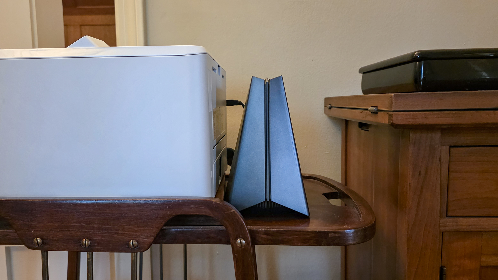A TP-Link Archer GE650 router on a table next to a printer