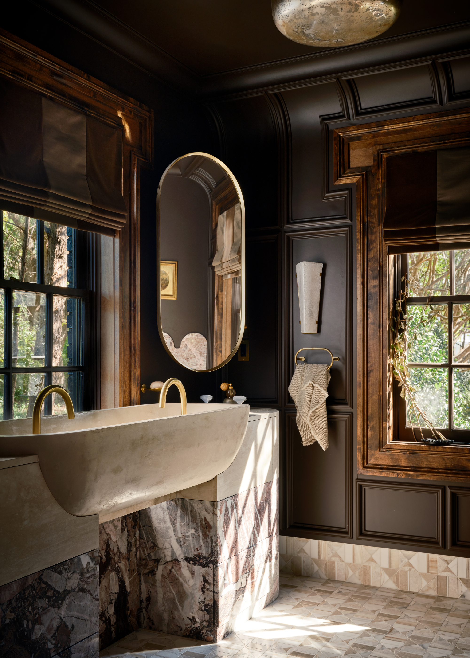 A bathroom with brown panelled walls and a double stone trough sink