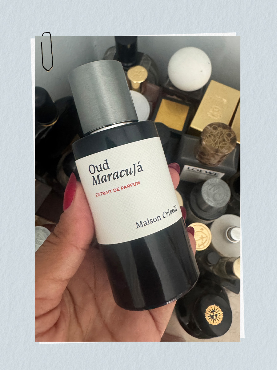 A photo of Rhea holding the Oud Maracuja perfume bottle from Maison Crivelli