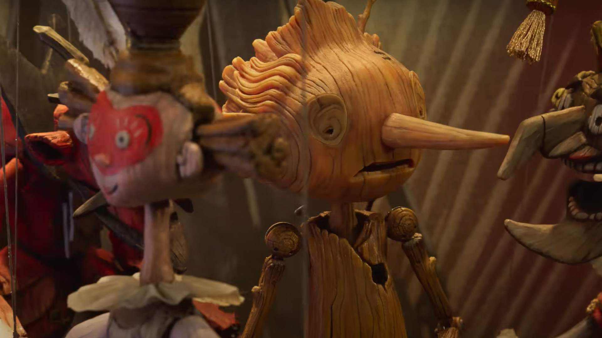 A screenshot of the trailer for the Netflix movie, Guillermo del Toro's Pinocchio, with Pinocchio talking to a wooden puppet.