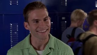 Stifler stands in the high school hallway wearing a green polo in American Pie