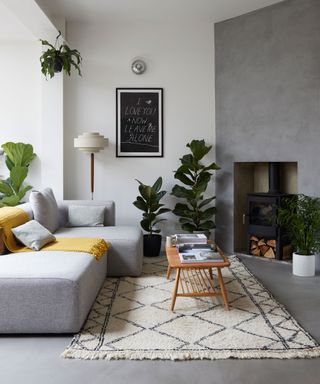 A mid-century modern living room with gray walls and flooring, a wooden coffee table and a gray sofa with yellow throw.