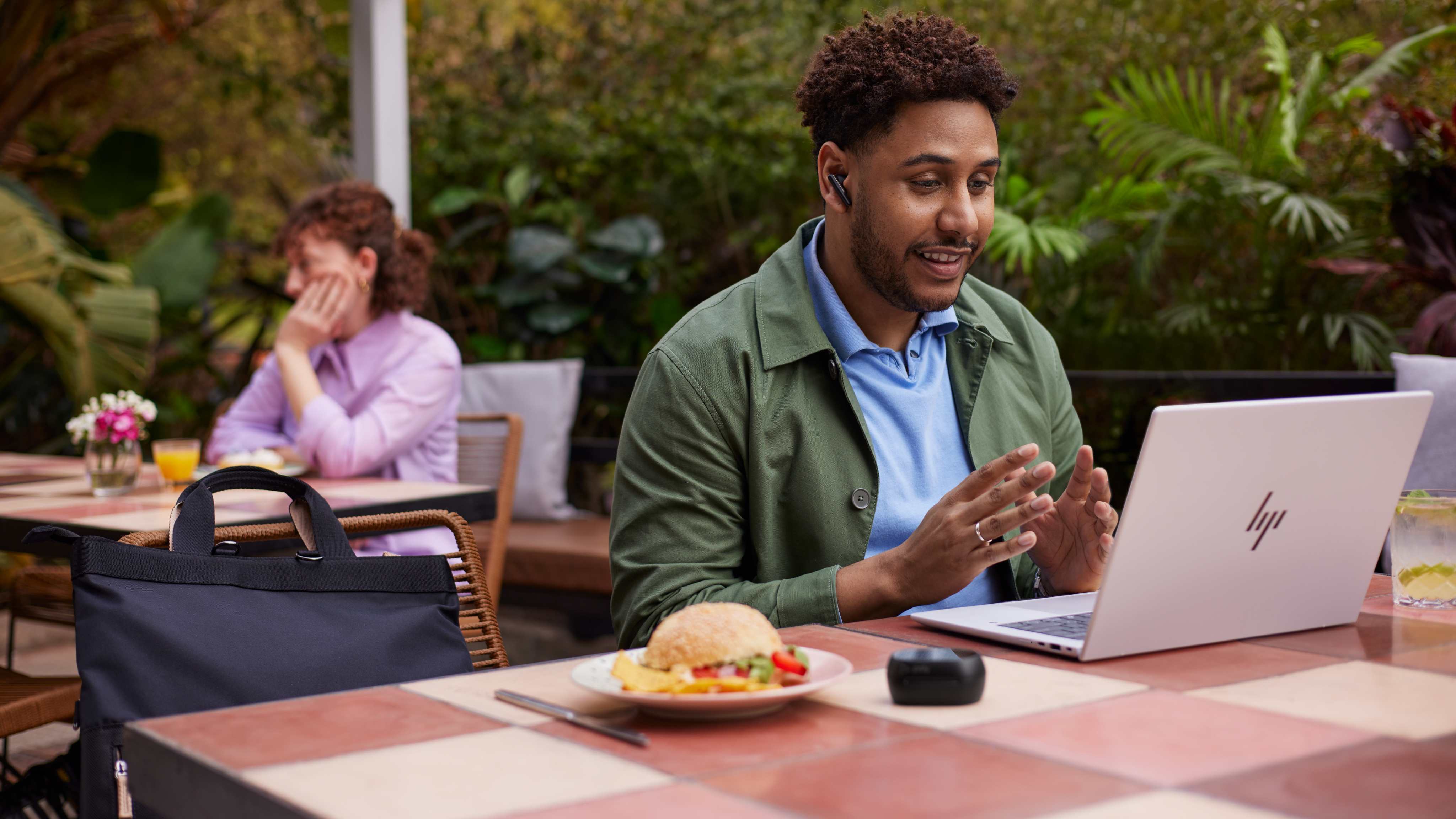 A man seated at a table, using the HP EliteBook X 14 (G1i) for video conferencing.