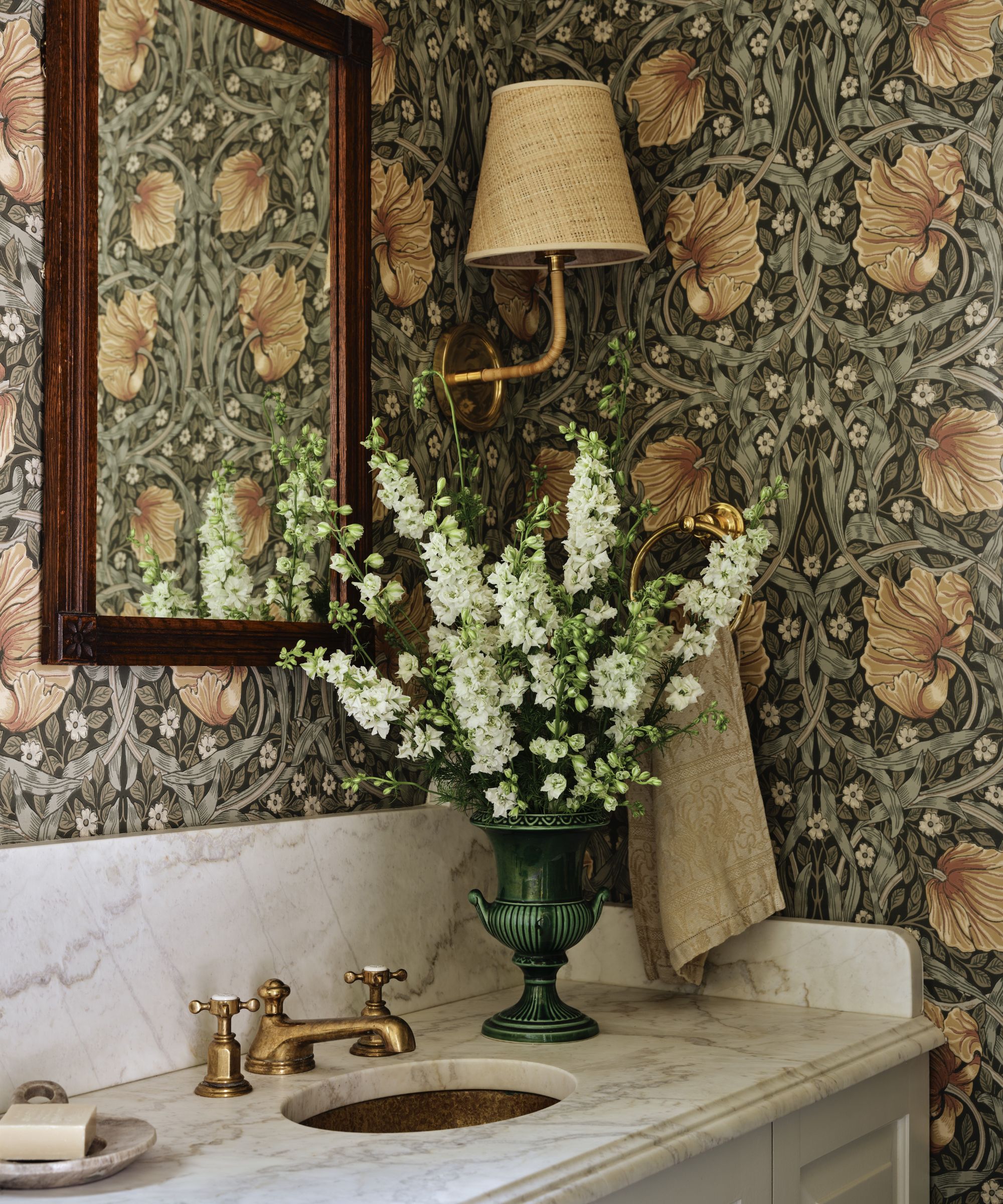 a small powder room with floral william morris wallpaper and compact marble vanity
