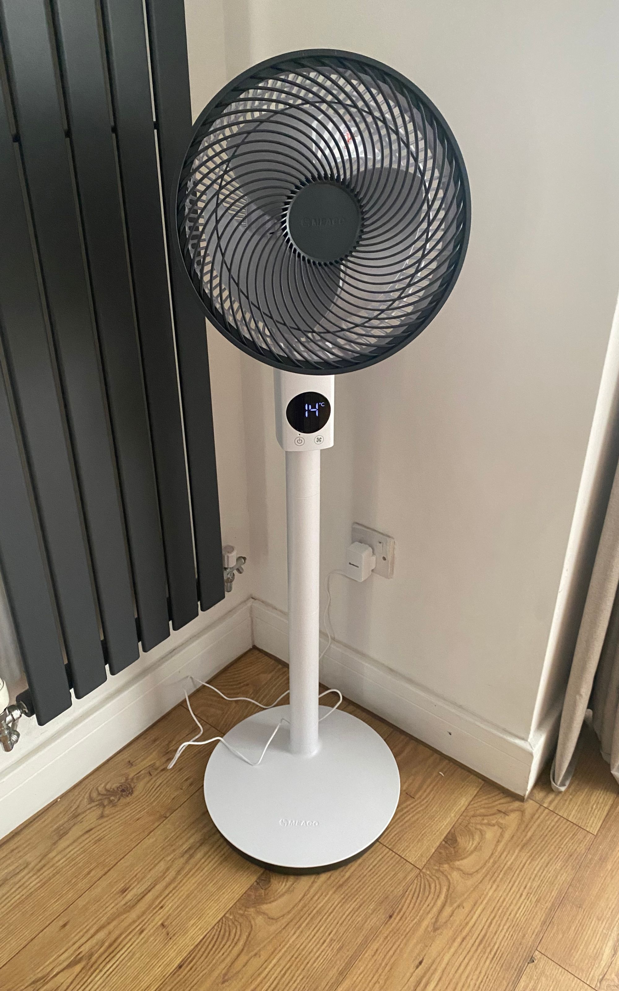 Meaco MeacoFan Sefte 10'' pedestal air circulator at full height, plugged in next to a grey vertical radiator