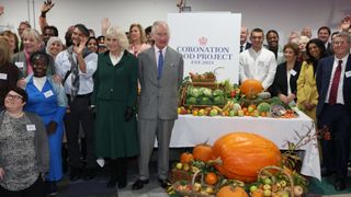 King Charles III and Queen Camilla pose for a photograph with staff during the launch of the Coronation Food Project