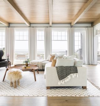 Large windows, wooden floor, ceiling and coffee table, white rug
