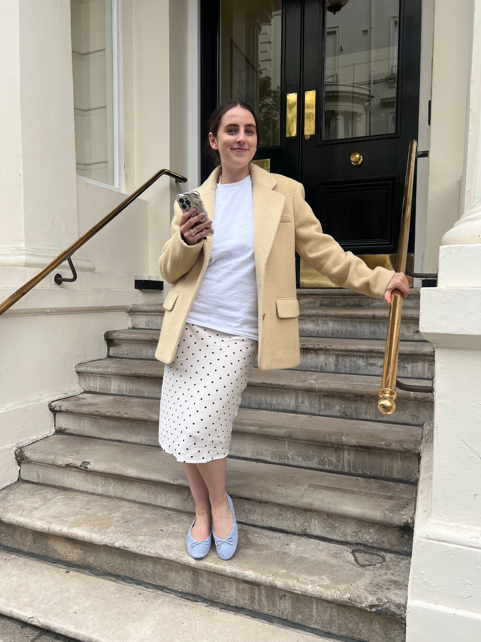 An image of Who What Wear UK's SEO writer Ava Gilchrist standing on a staircase wearing the Reformation Suzanne Ballet flats.