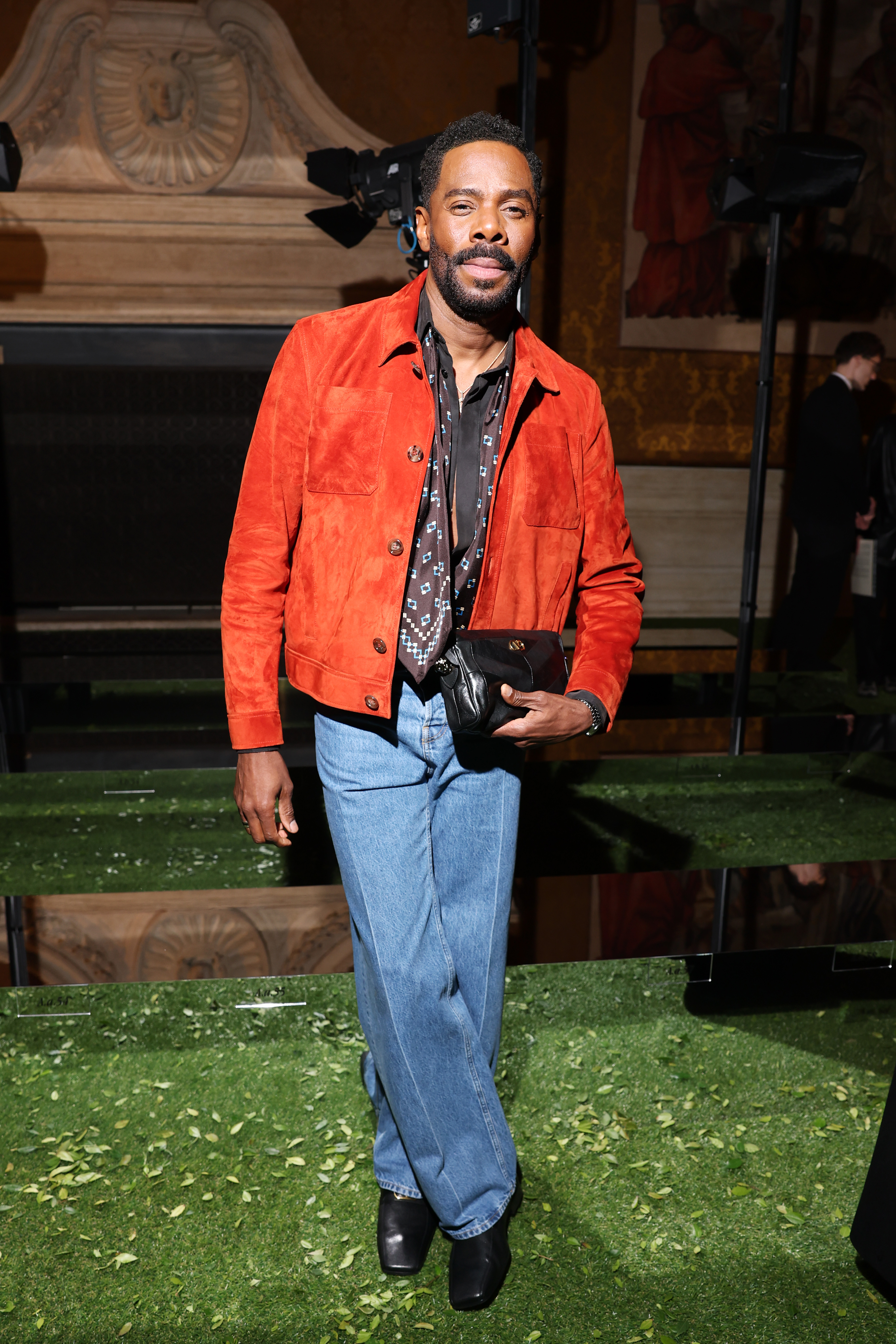 Colman Domingo wearing an orange jacket, jeans, and black shoes
