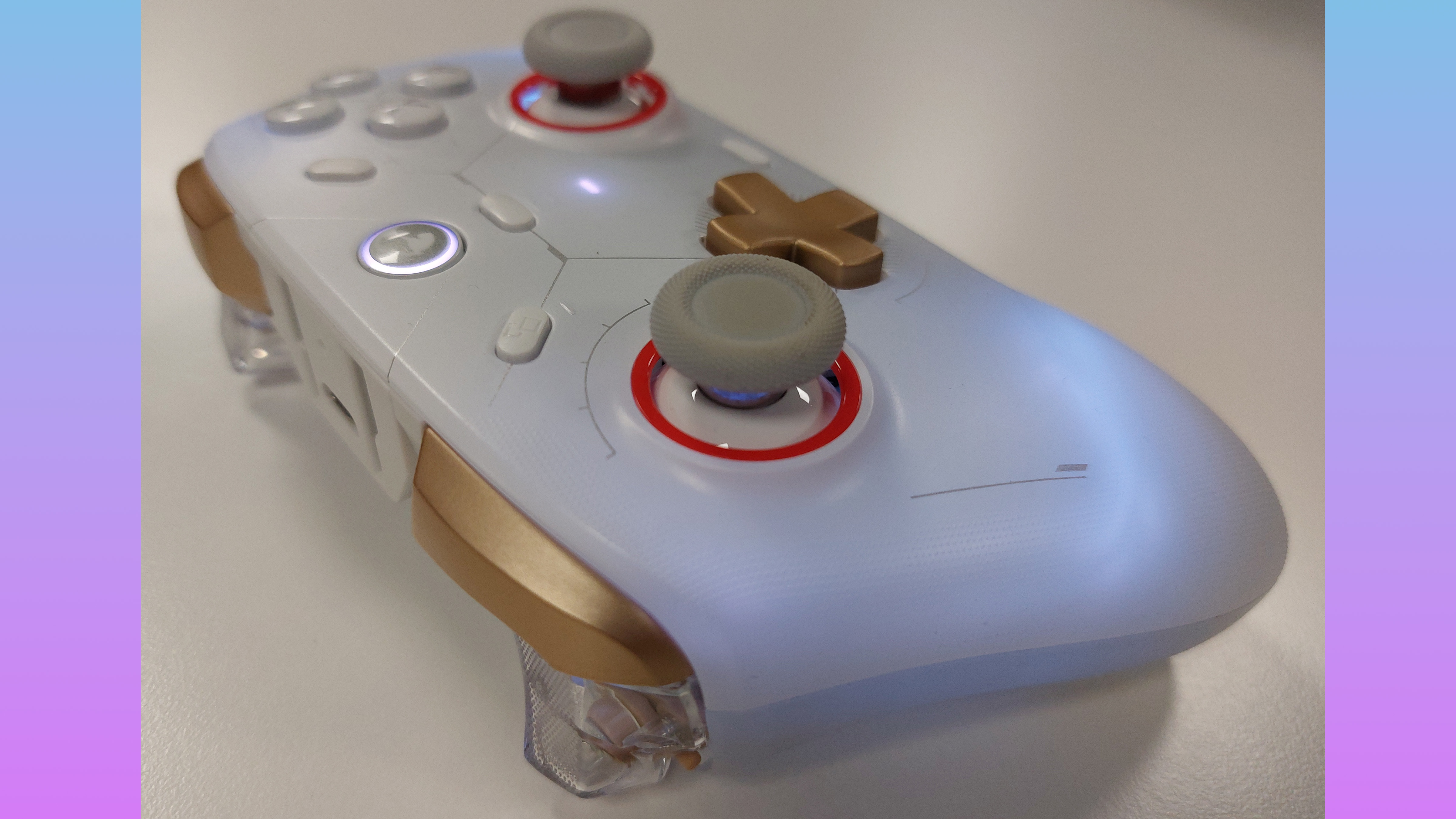 The GameSir Cyclone 2 controller in Phantom White. This colourway features a white gamepad body, a golden D-pad, golden shoulder buttons, clear plastic triggers, grey thumbstick covers with orange thumbstick inlays, and silver text accents. The RGB lights are switched on in this image, emitting a pale white light through the frosted plastic of the controller's body.