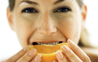 Woman biting into an orange slice