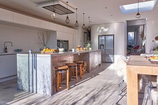 industrial open plan kitchen diner with a metal island and cage pendant lights