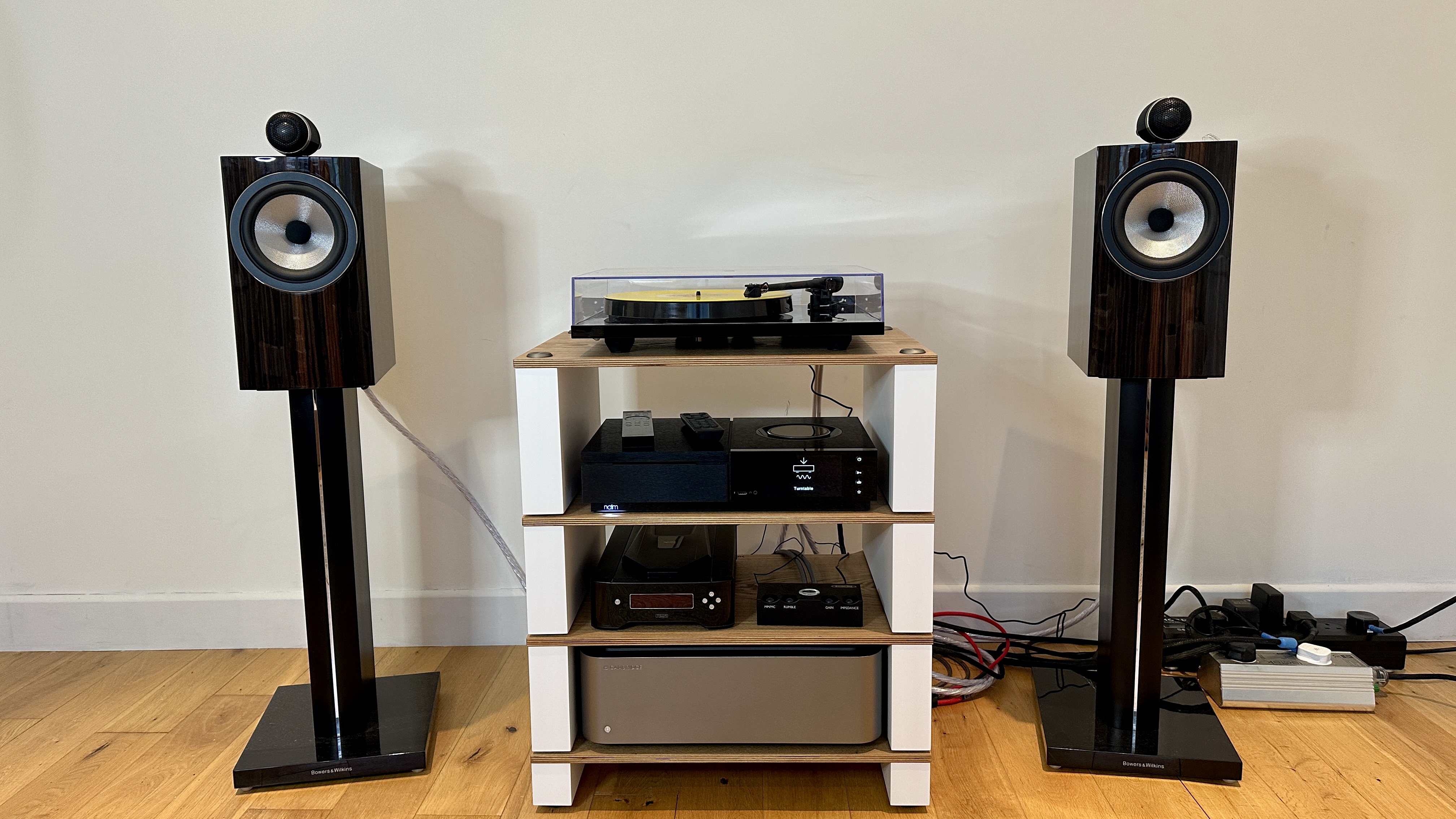 Goldring GR3 turntable on top of a four-shelf sound system with pre-amp and stand mount speakers.