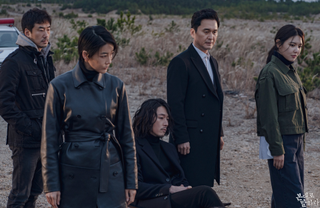 five people look down and to the right, while standing in a desert field, in the korean drama 'tell me what you saw'