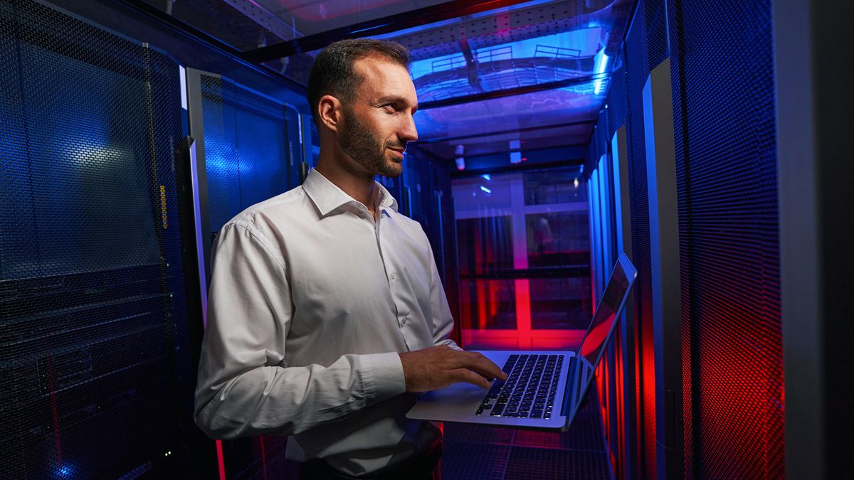 man working on laptop in data centre