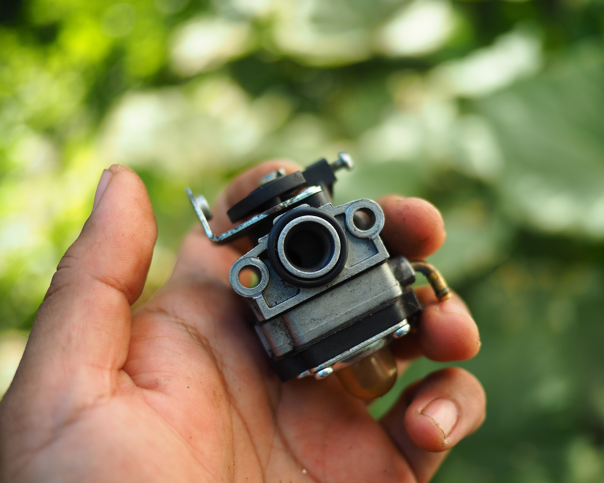 hand holding lawn mower carburetor