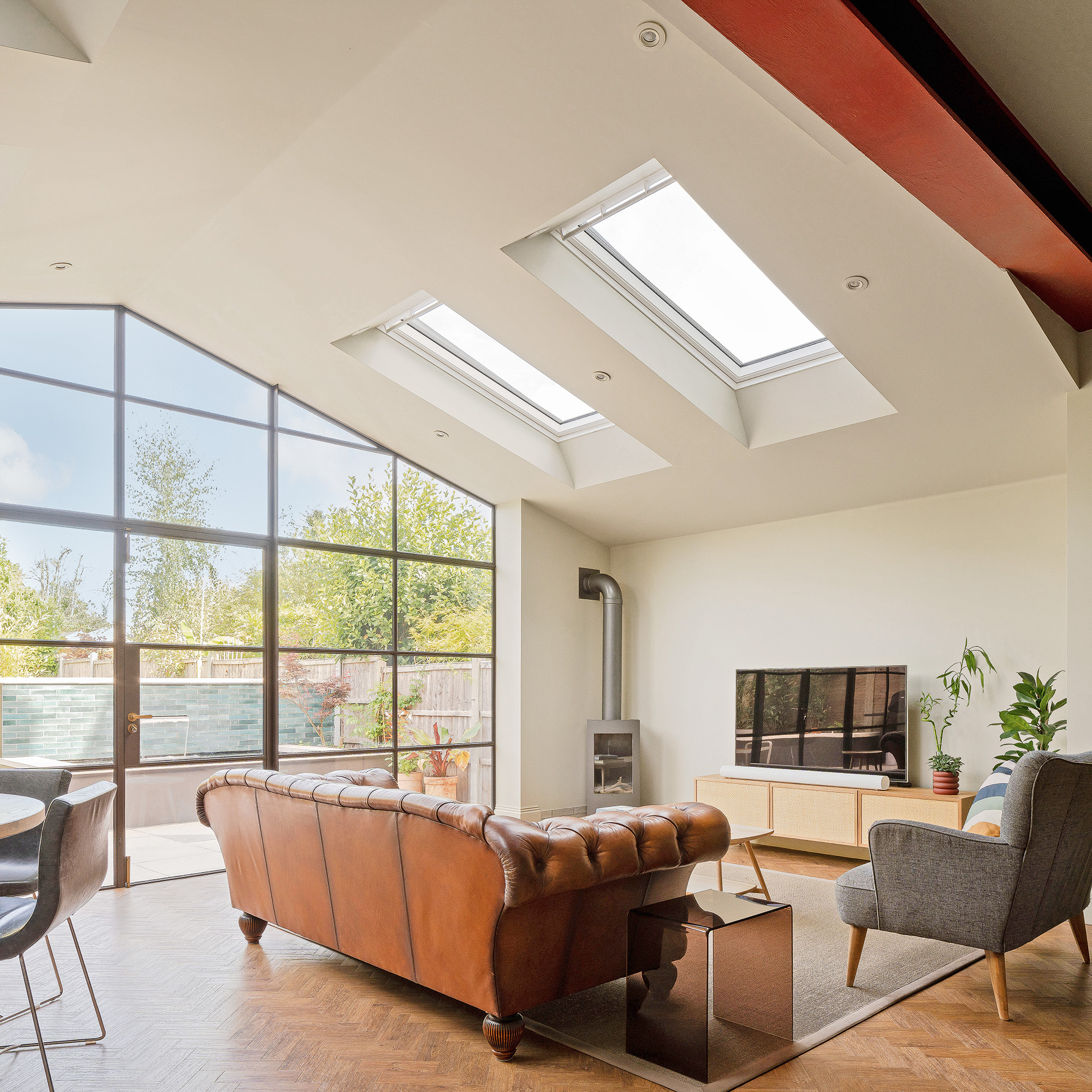 open plan kitchen living area with leather sofa, wood burning stove in corner and crittall patio doors