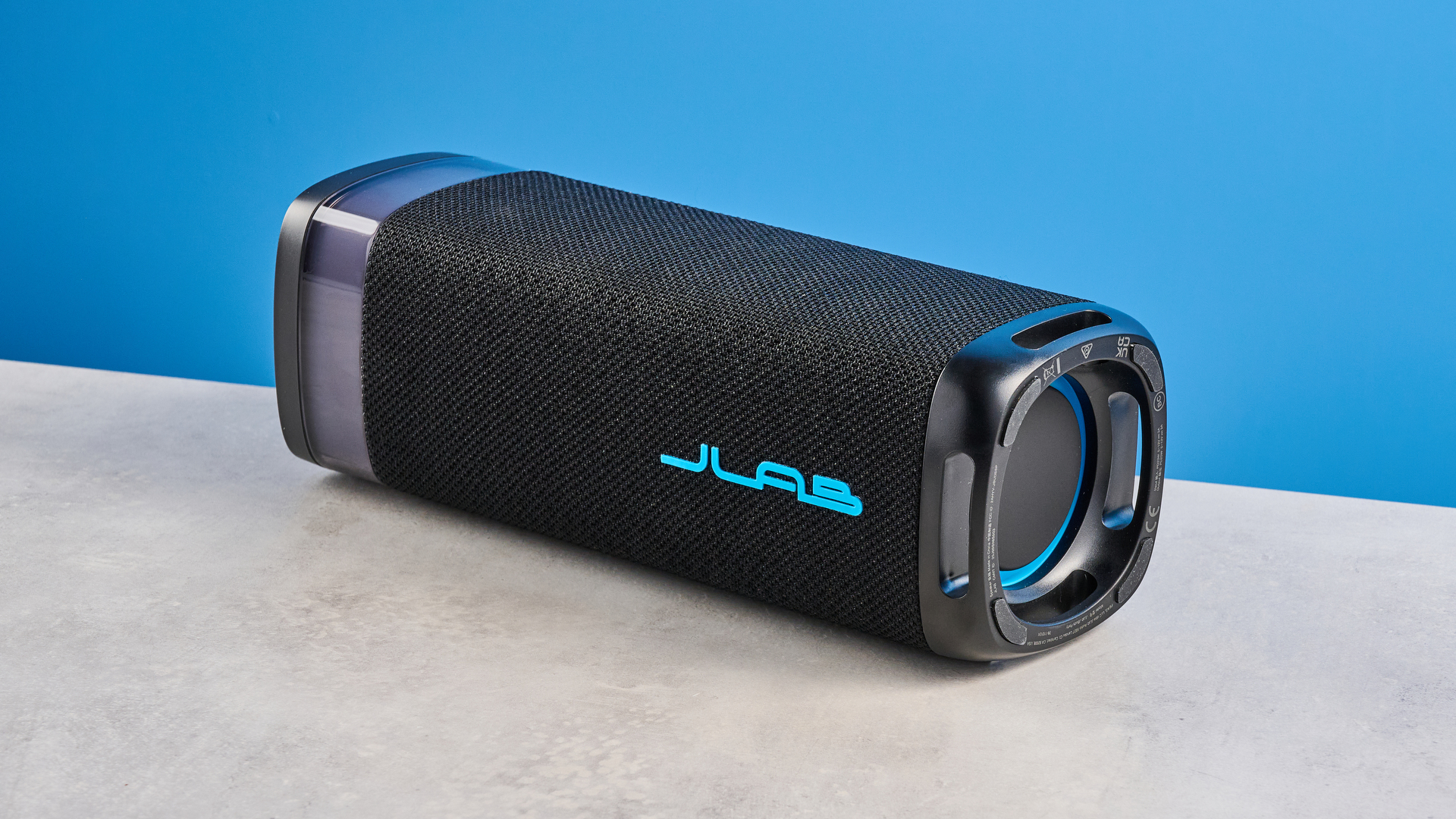 the jlab jbuds party speaker with LED rainbow lights photographed against a blue background