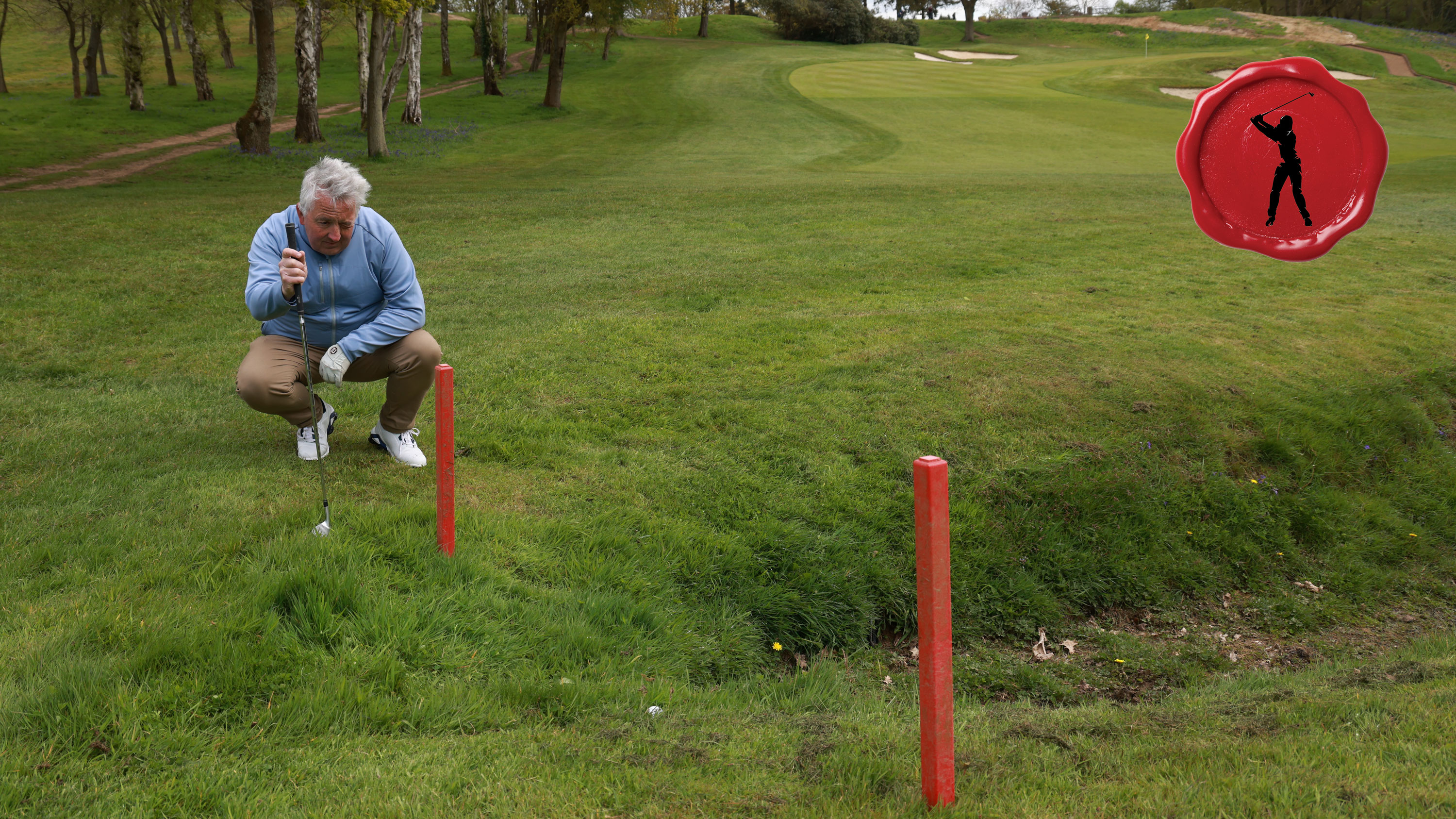a golfer looking at two red stakes near a penalty area