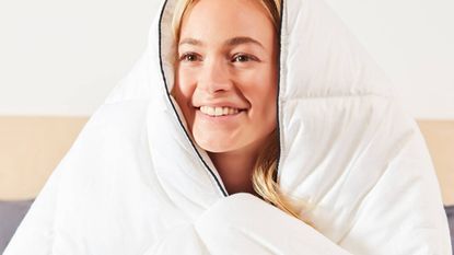 Woman wrapped up in a Panda London duvet while smiling