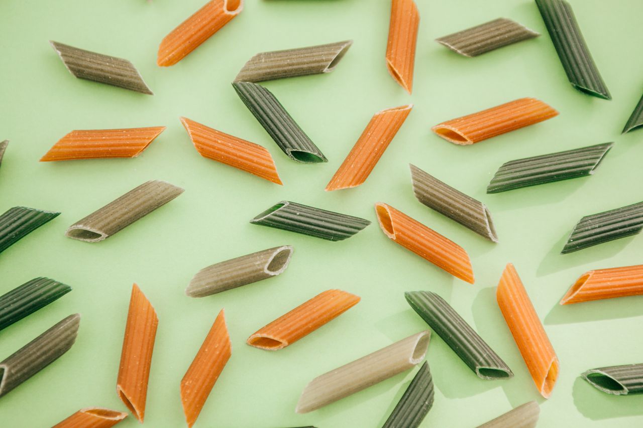 Raw multicolor pasta against a green background