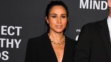 Meghan Markle poses for photographs wearing a black suit and gold necklace at Project Healthy Minds' World Mental Health Day Festival held at Spring Studios on October 9, 2025