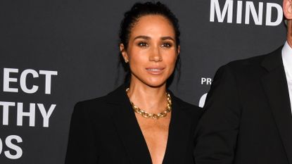 Meghan Markle poses for photographs wearing a black suit and gold necklace at Project Healthy Minds' World Mental Health Day Festival held at Spring Studios on October 9, 2025