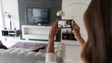 A woman takes video of the contents of her living room.