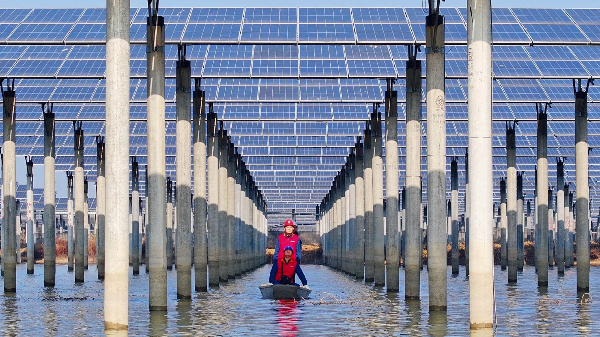 Chinese workers inspect installation of solar panels by boat
