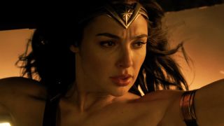 Gal Gadot's Diana holding up tank as flames surround her in the 2017 Wonder Woman movie