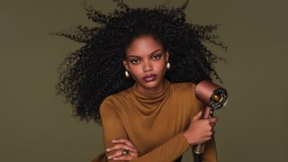 Woman holding Dyson hair styler in Plum and Copper colorway
