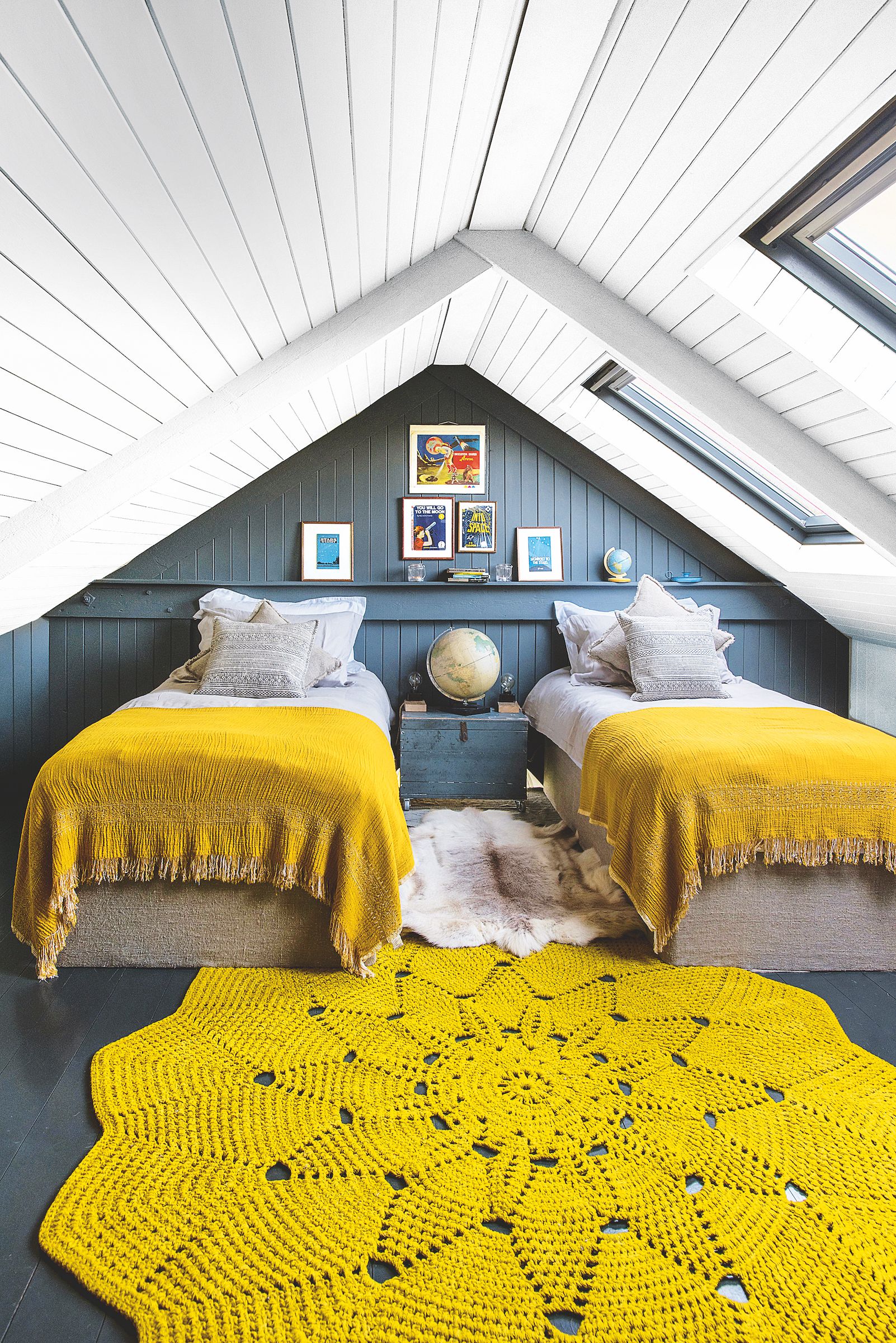 twin bedroom with dark blue walls and ochre covers and rug