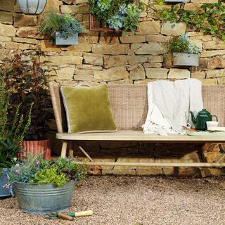 Garden bench in front of brick wall with potted plants surrounding