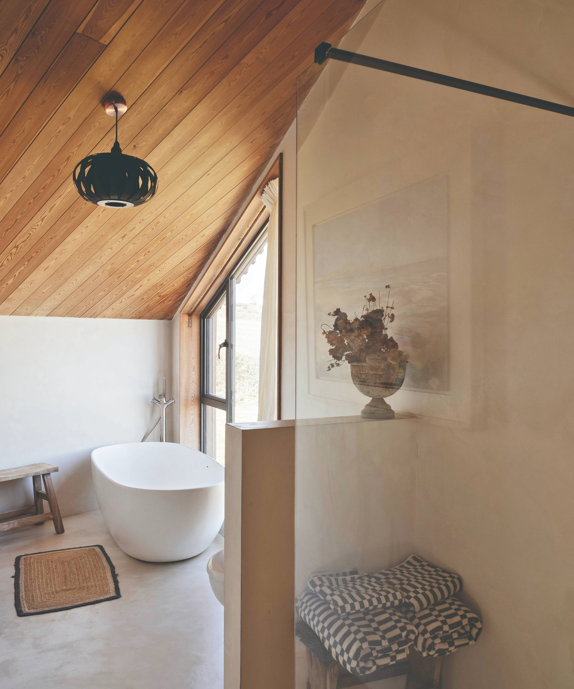 Bathroom with wooden sloped ceiling and freestanding bath