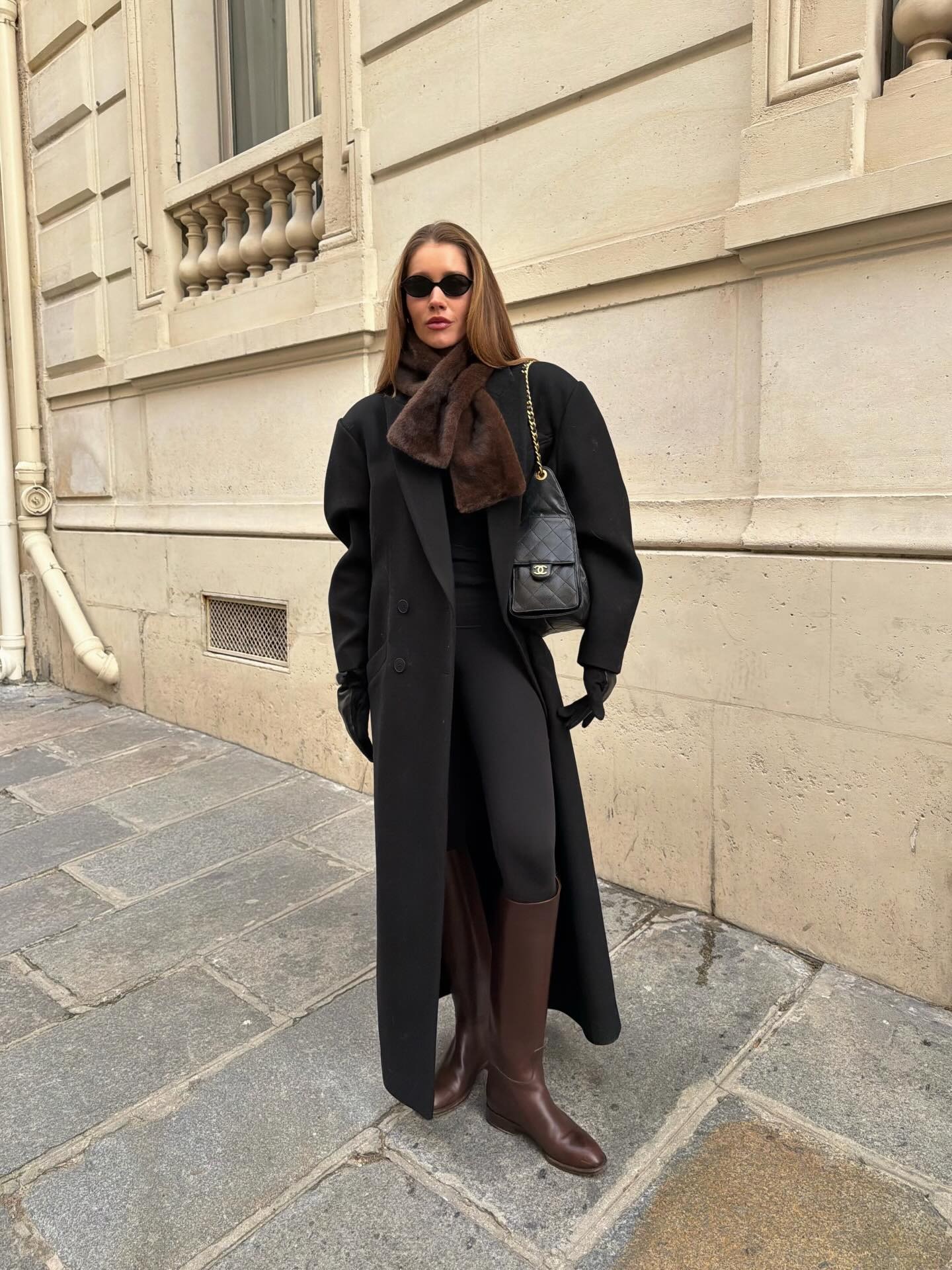 Woman in a long black coat and brown leather knee-high boots
