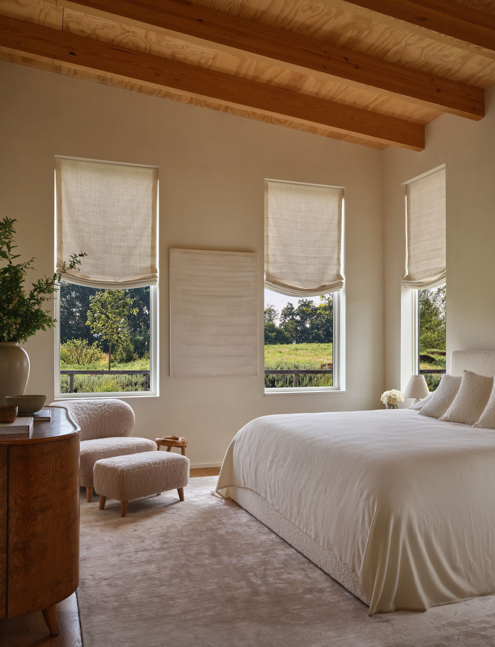 bedroom with a white bed and white pillows and three windows
