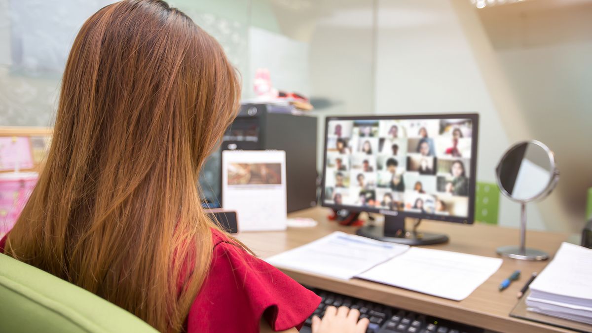 A person with long hair communicating with colleagues using video conferencing