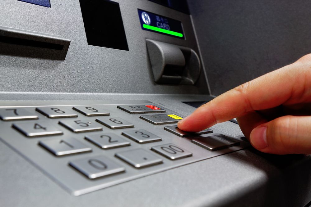 Person entering their PIN number into an ATM machine