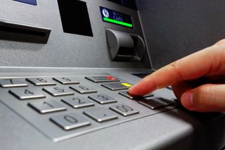 Person entering their PIN number into an ATM machine