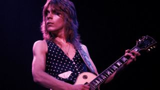 A photograph of Randy Rhoads on stage playing a Gibson Les Paul guitar