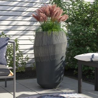 A tall architectural plant pot on a white deck