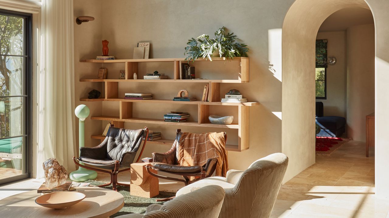 Sitting area with magnolia limewash walls, wood bookshelf and brown leather armchairs